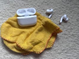 AirPods case next to a cleaning cloth and earbuds.