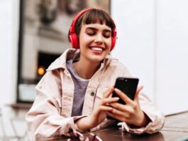 A girl looks at her phone while wearing headphones