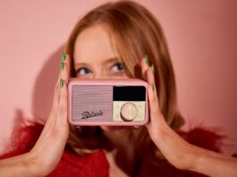 Roberts Revival Petite 2 in pink, held by a redheaded-lady wearing green nail polis, in a pink room