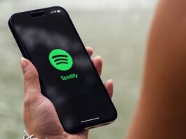 Hand holding a phone with the Spotify app logo